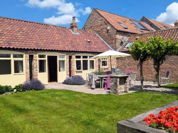 Charming cottage courtyard with garden and patio furniture.