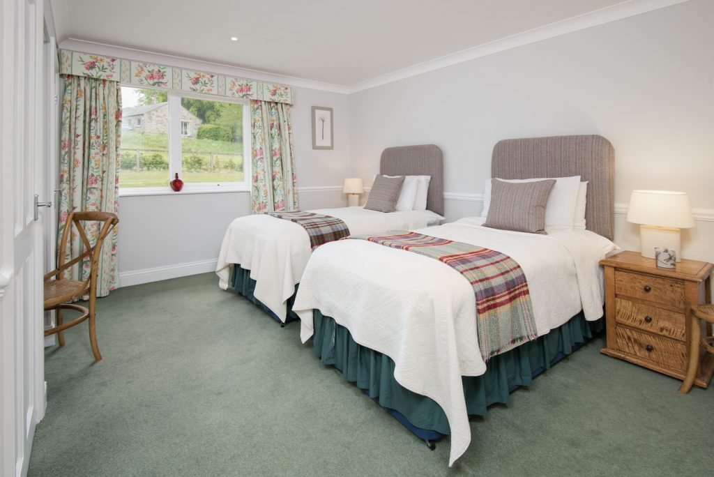 Twin bedroom with countryside view and floral curtains.