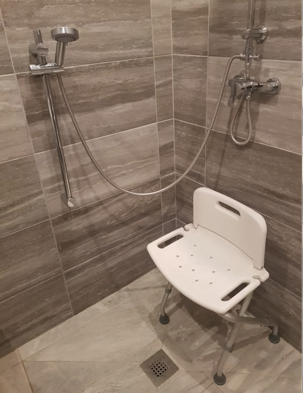 Shower with accessible chair and handheld showerhead.