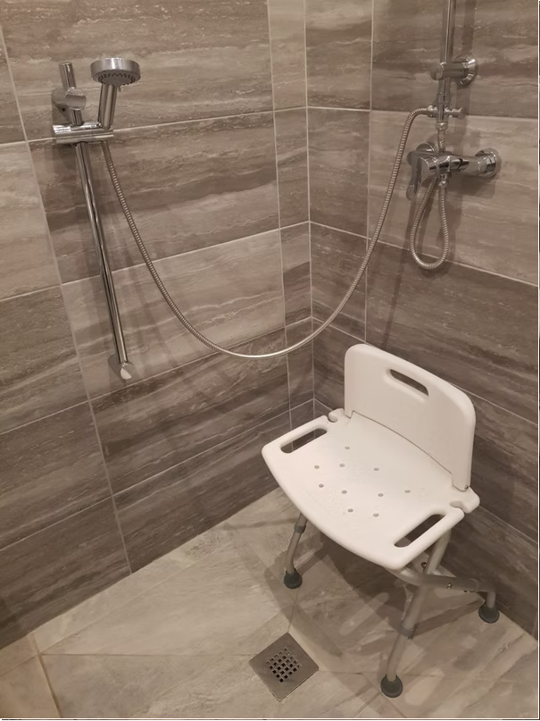 Shower with accessible chair and handheld showerhead.
