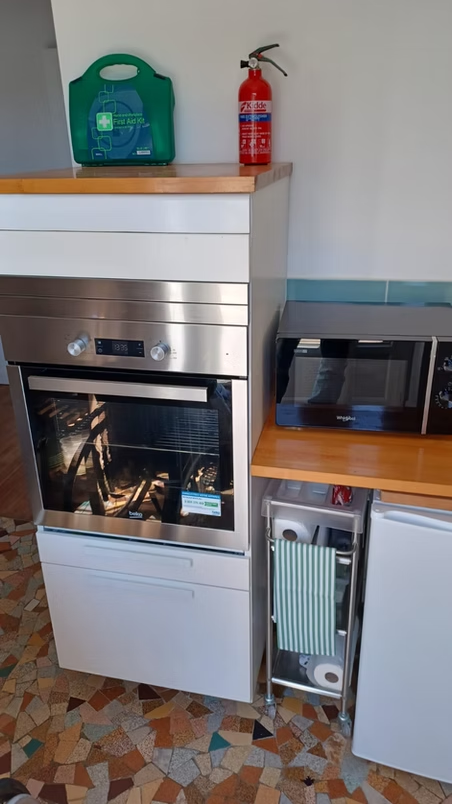 Modern kitchen with oven, microwave, fire extinguisher, first aid kit.
