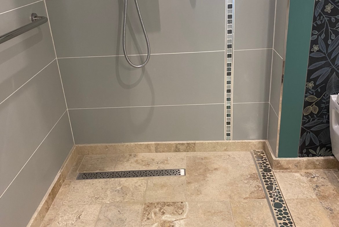Modern tiled shower floor with chrome fixtures.