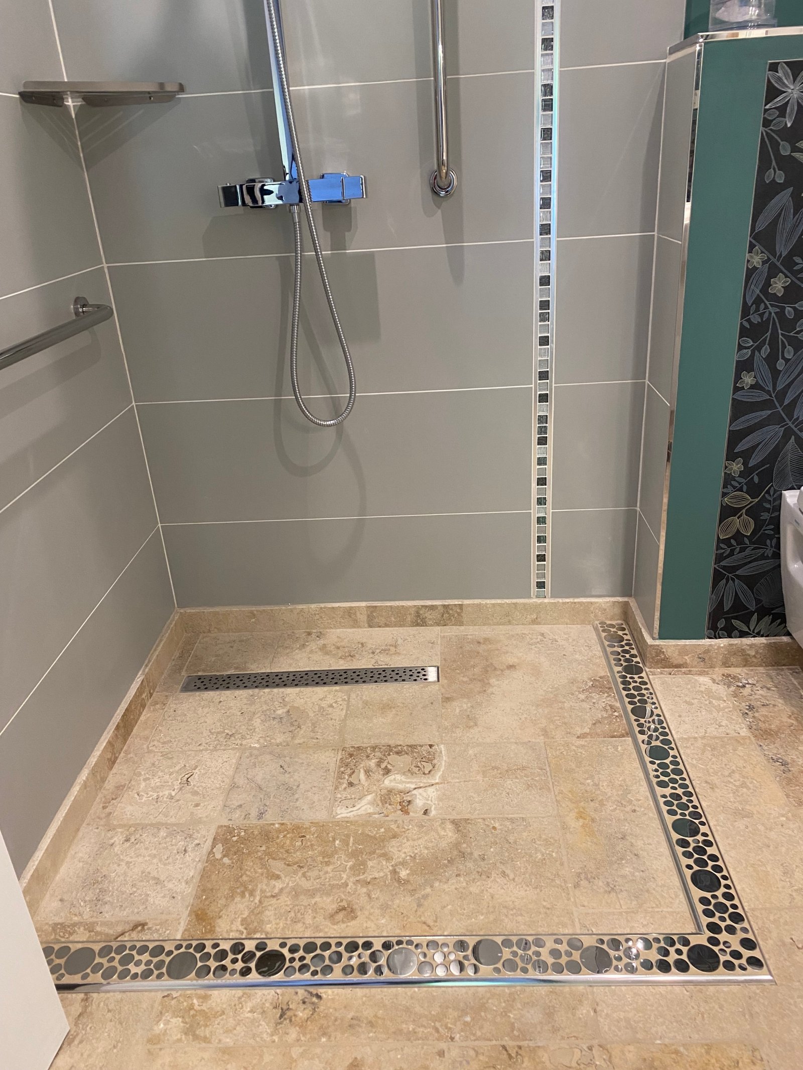 Modern tiled shower floor with chrome fixtures.