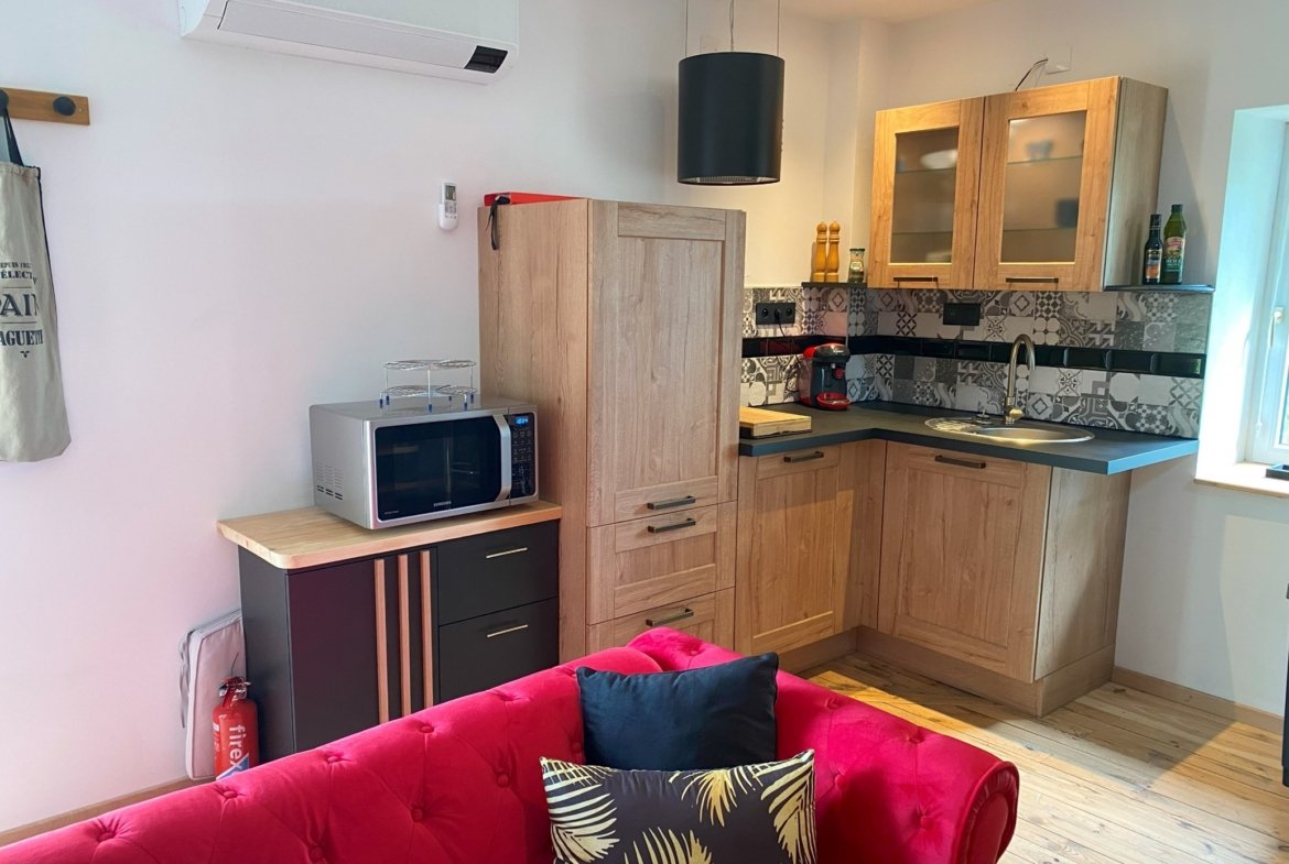 Modern kitchen with wooden cabinets and red sofa.