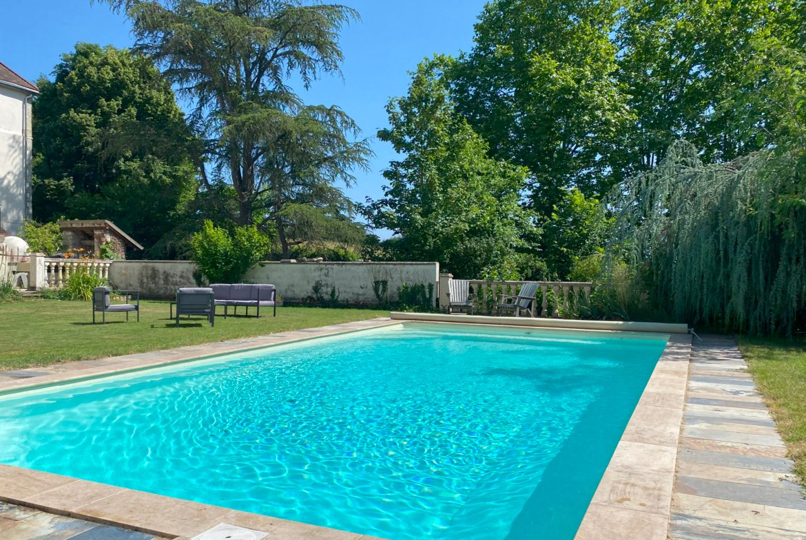 Garden swimming pool with chairs and trees.
