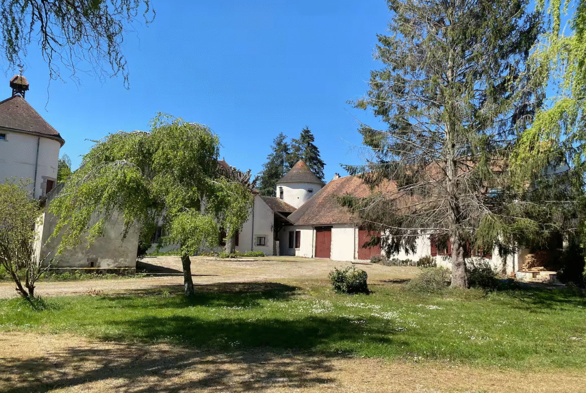 French countryside farmhouse with trees and clear sky.