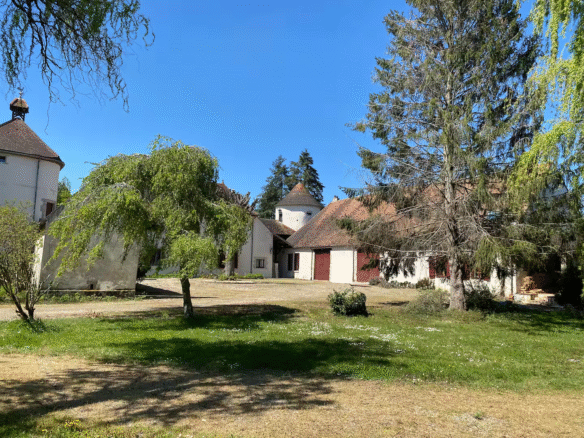 French countryside farmhouse with trees and clear sky.