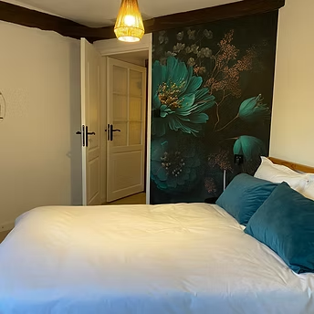 Cosy bedroom with floral wallpaper and double bed.