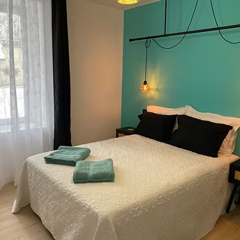 Cosy bedroom with teal accent wall and lamp.