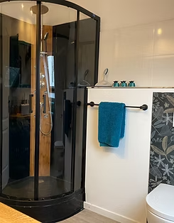 Modern bathroom with glass shower and blue towel.
