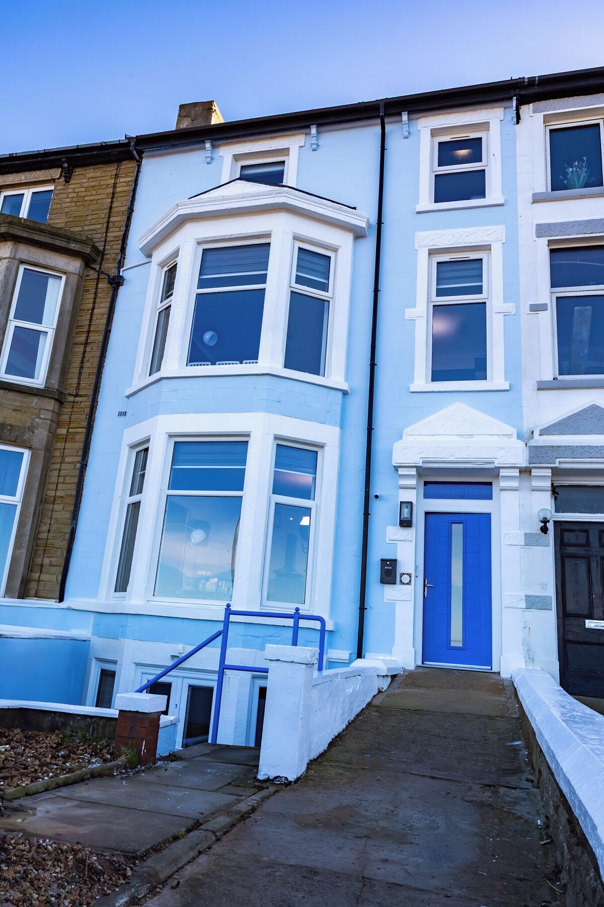Blue terraced house with bay windows and blue door.