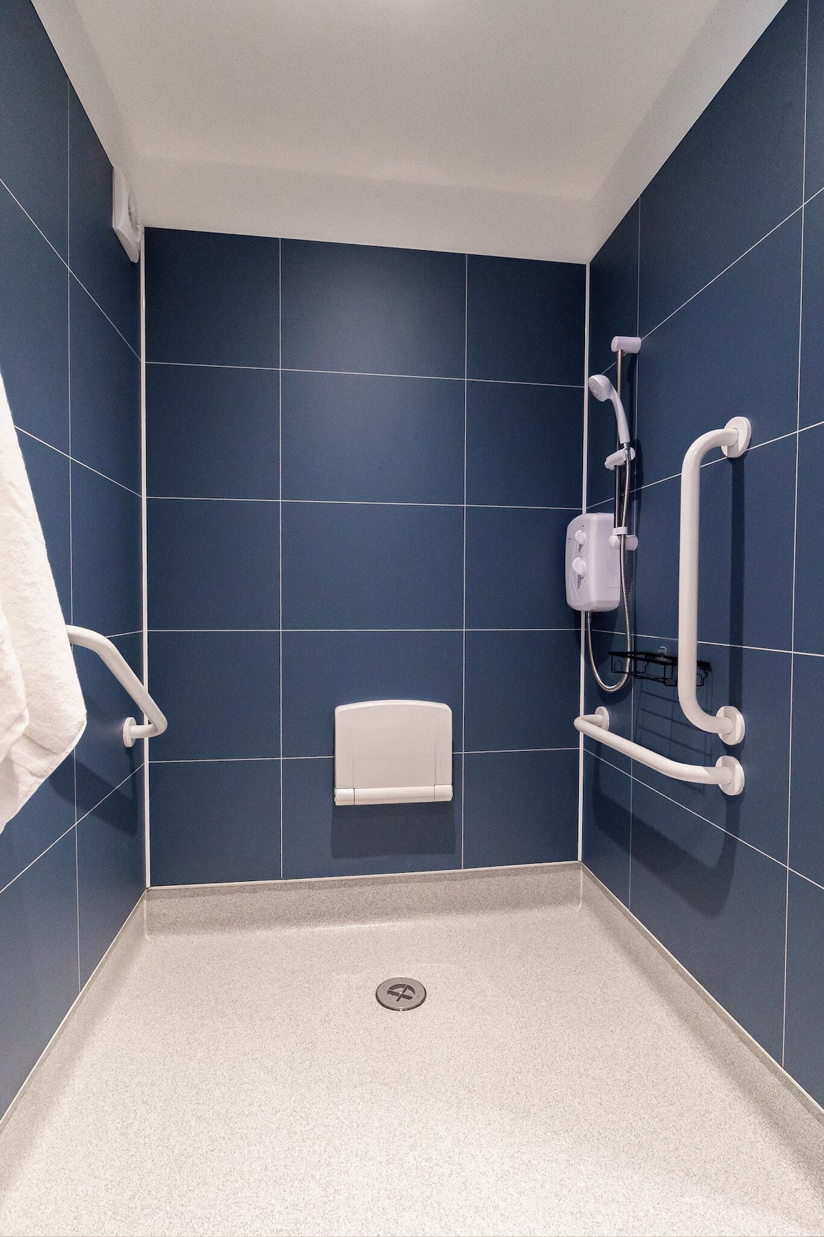 Accessible shower with grab bars and foldable seat.