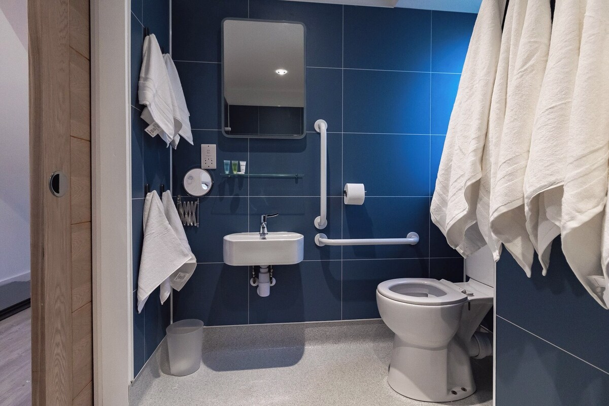 Accessible bathroom with blue tiles and handrails.