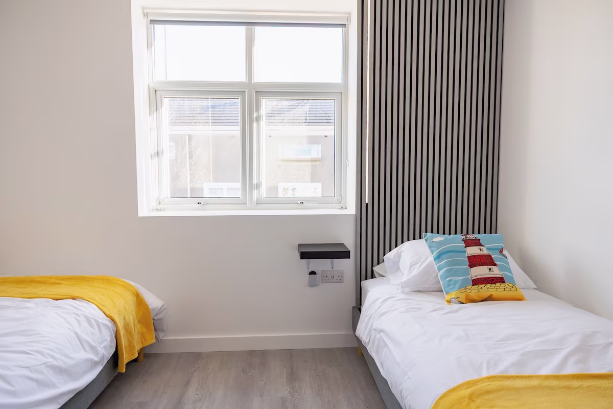 Twin beds with colourful pillows in bright bedroom.