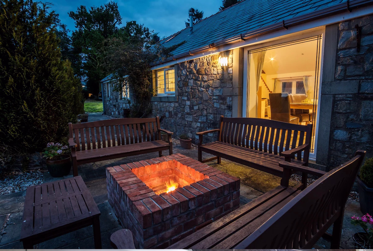 Cosy patio with fire pit and benches at dusk.