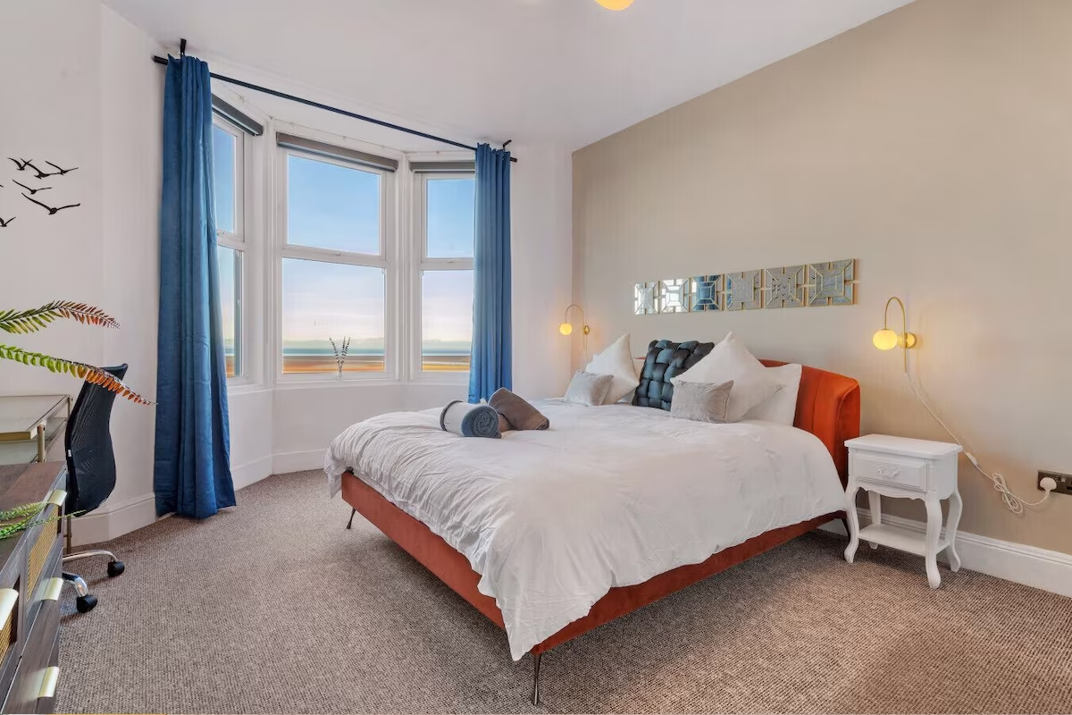 Coastal bedroom with sea view and blue curtains.