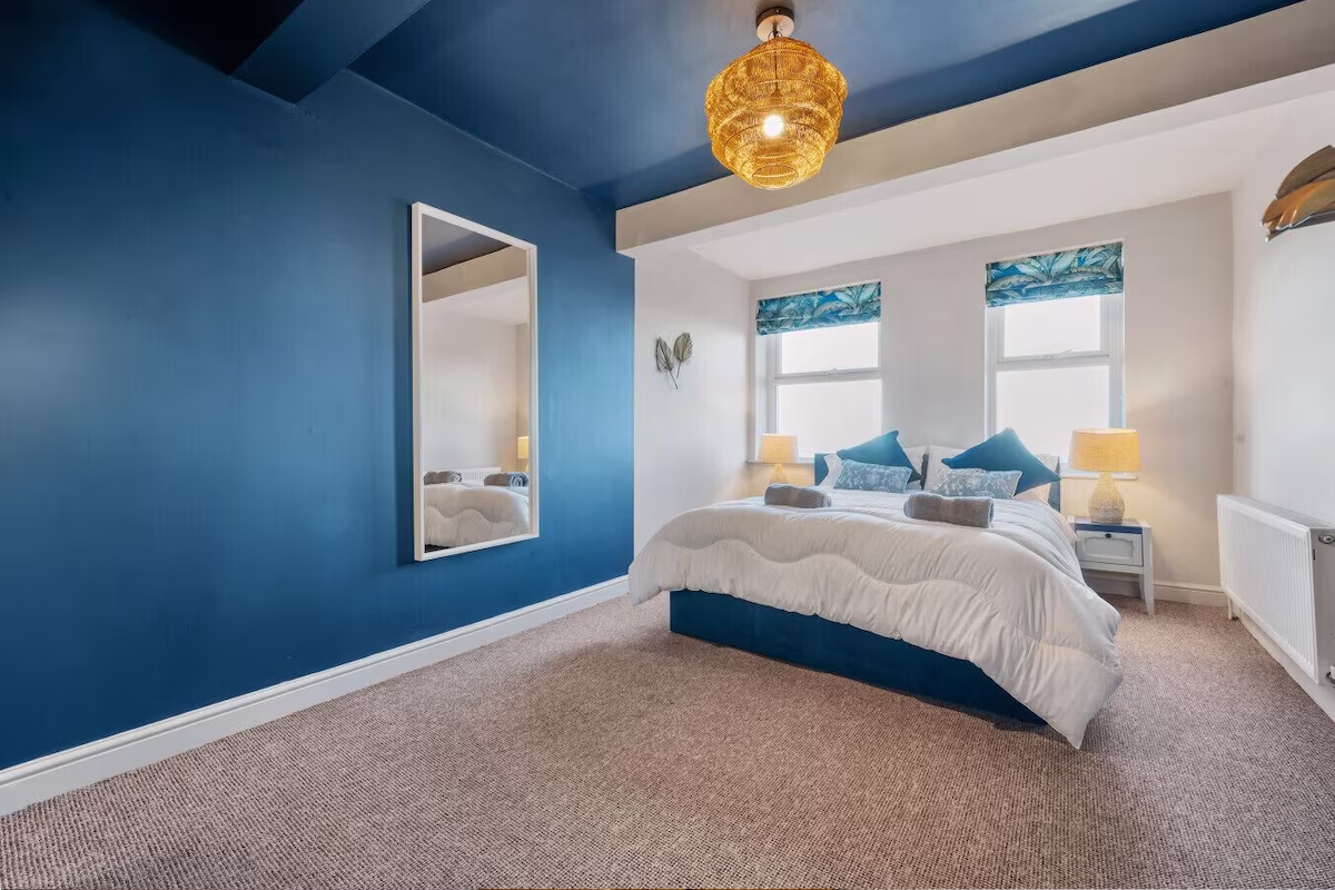 Modern bedroom with blue walls and decor.