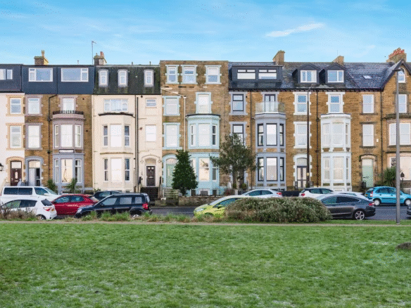 Row of terraced houses with parked cars.