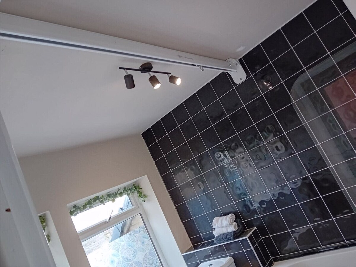 Modern bathroom with black tiled wall and spotlights