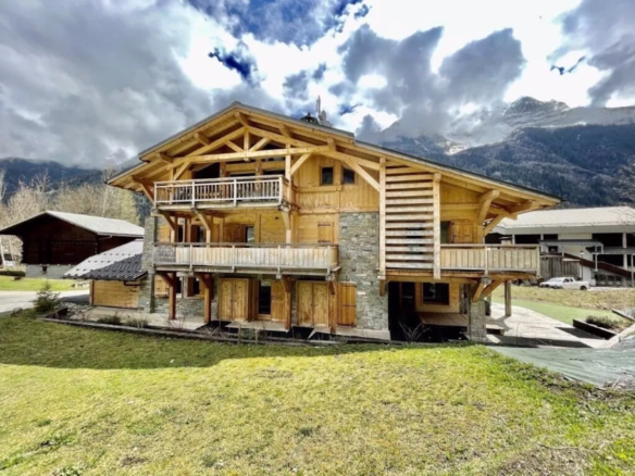 Wooden chalet in mountainous landscape under cloudy skies.