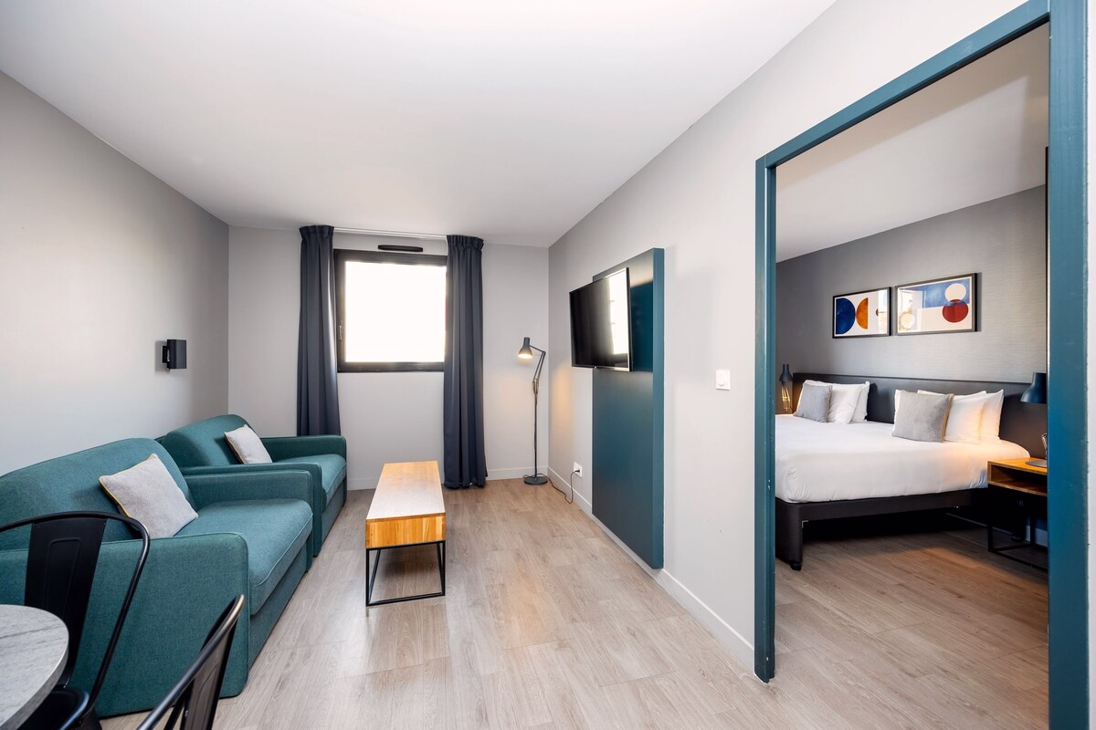 Modern hotel suite with sitting area and bedroom.