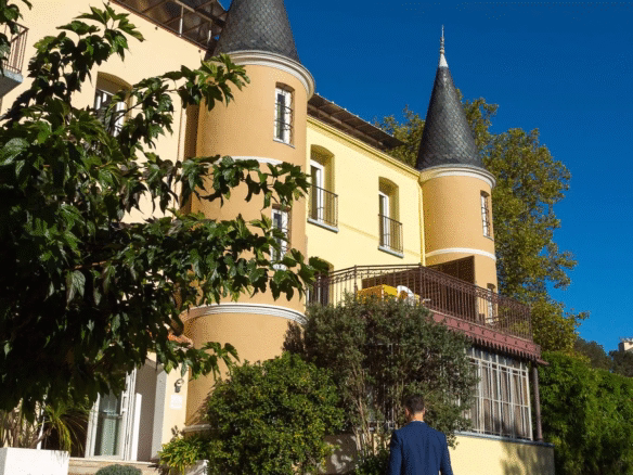 Man in suit pulling suitcase towards castle-like building.