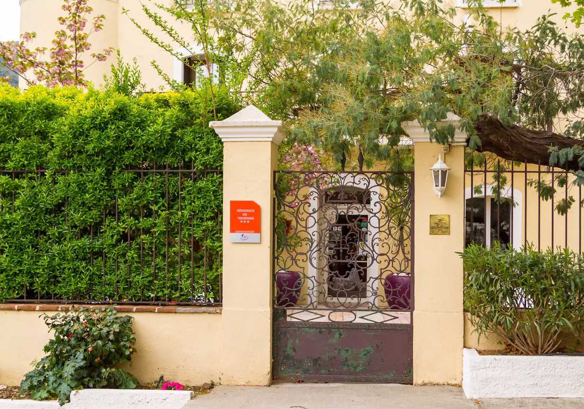 Decorative gated entrance with greenery and sign.