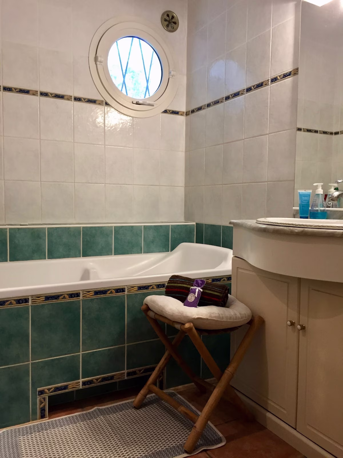 Modern bathroom with bathtub and round window.