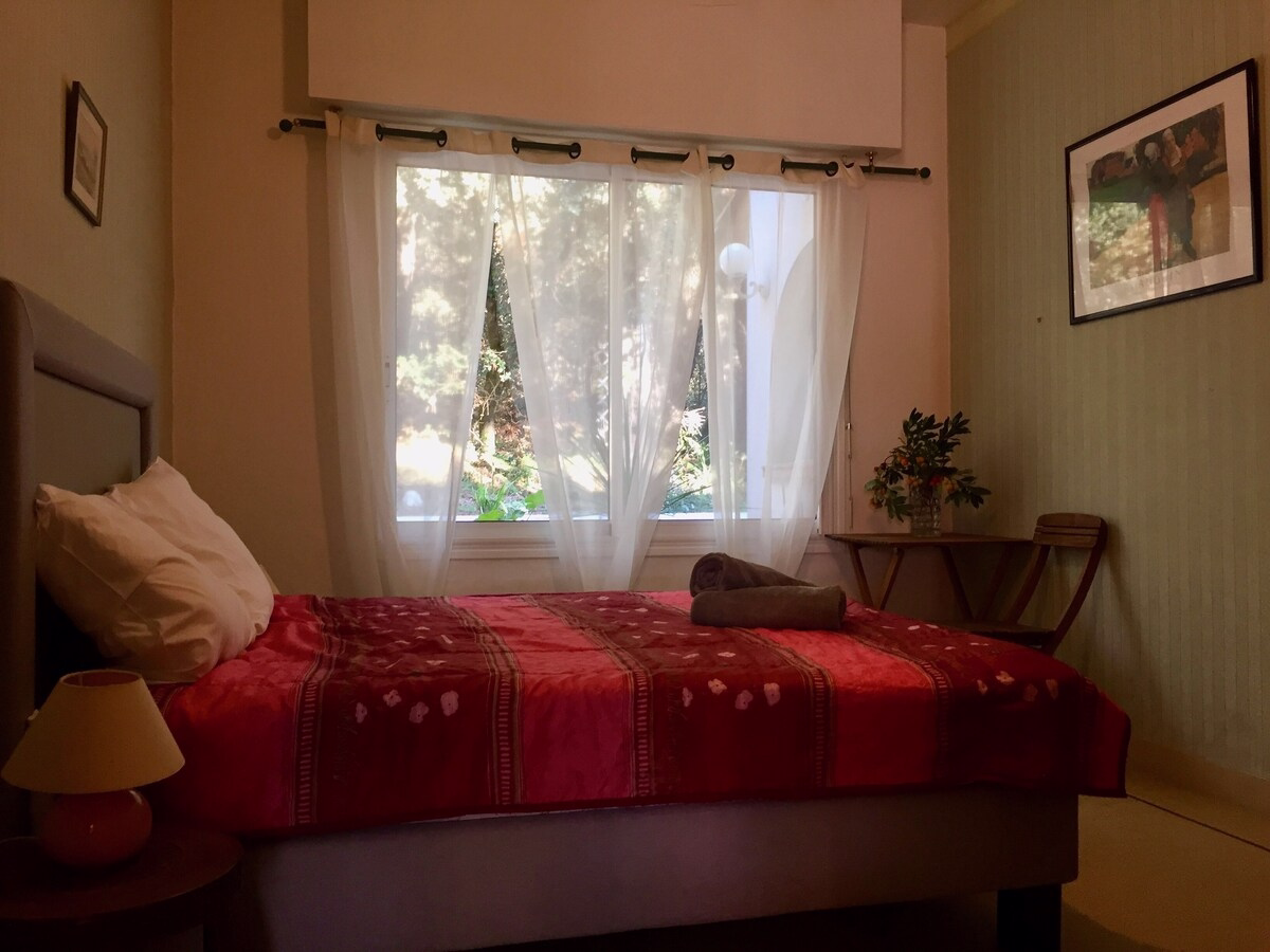 Cosy bedroom with red bedding and large window.