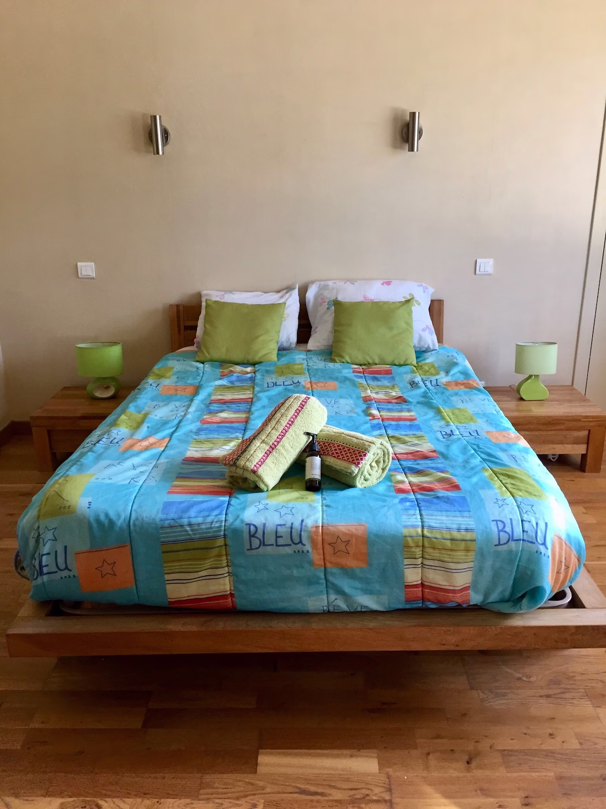Colourful double bed with towels and toiletries.