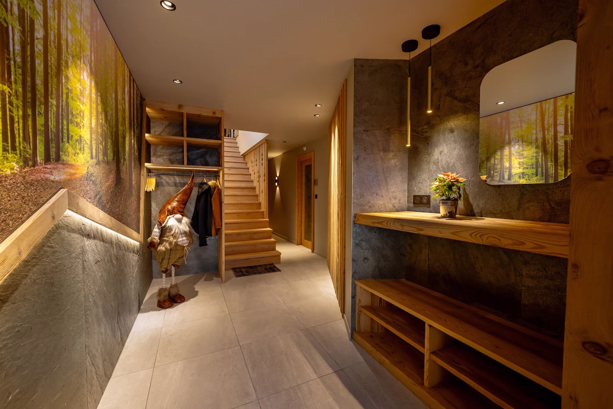 Modern hallway with wooden stairs and forest mural.