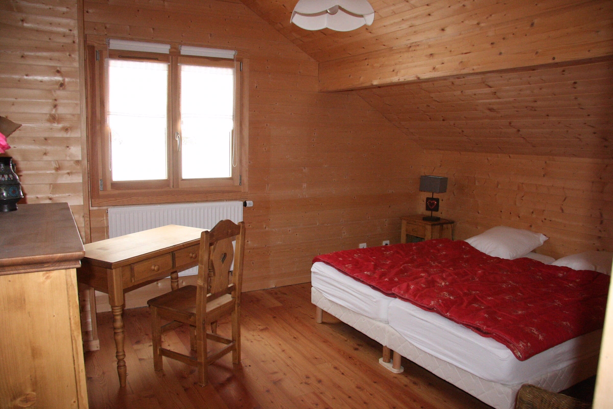 Cosy wooden bedroom with double bed and desk.