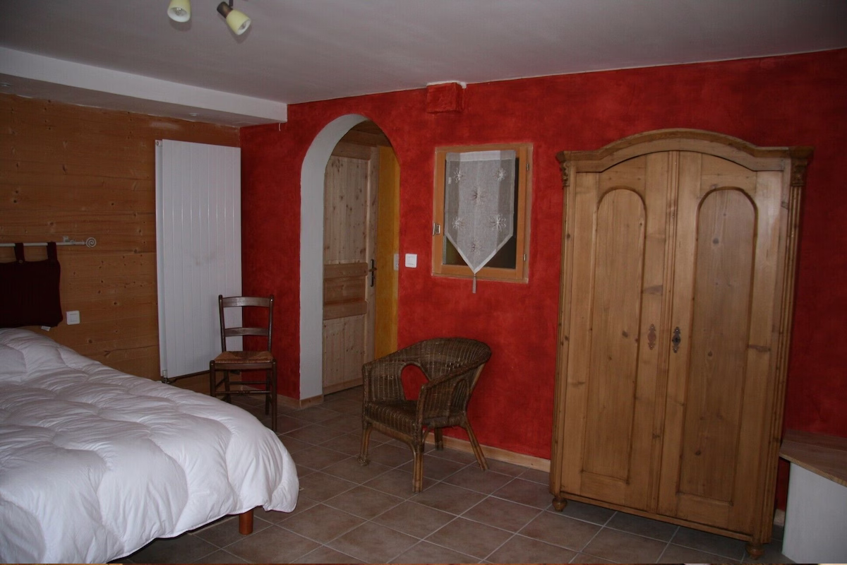 Cosy bedroom with red rustic walls and furniture.