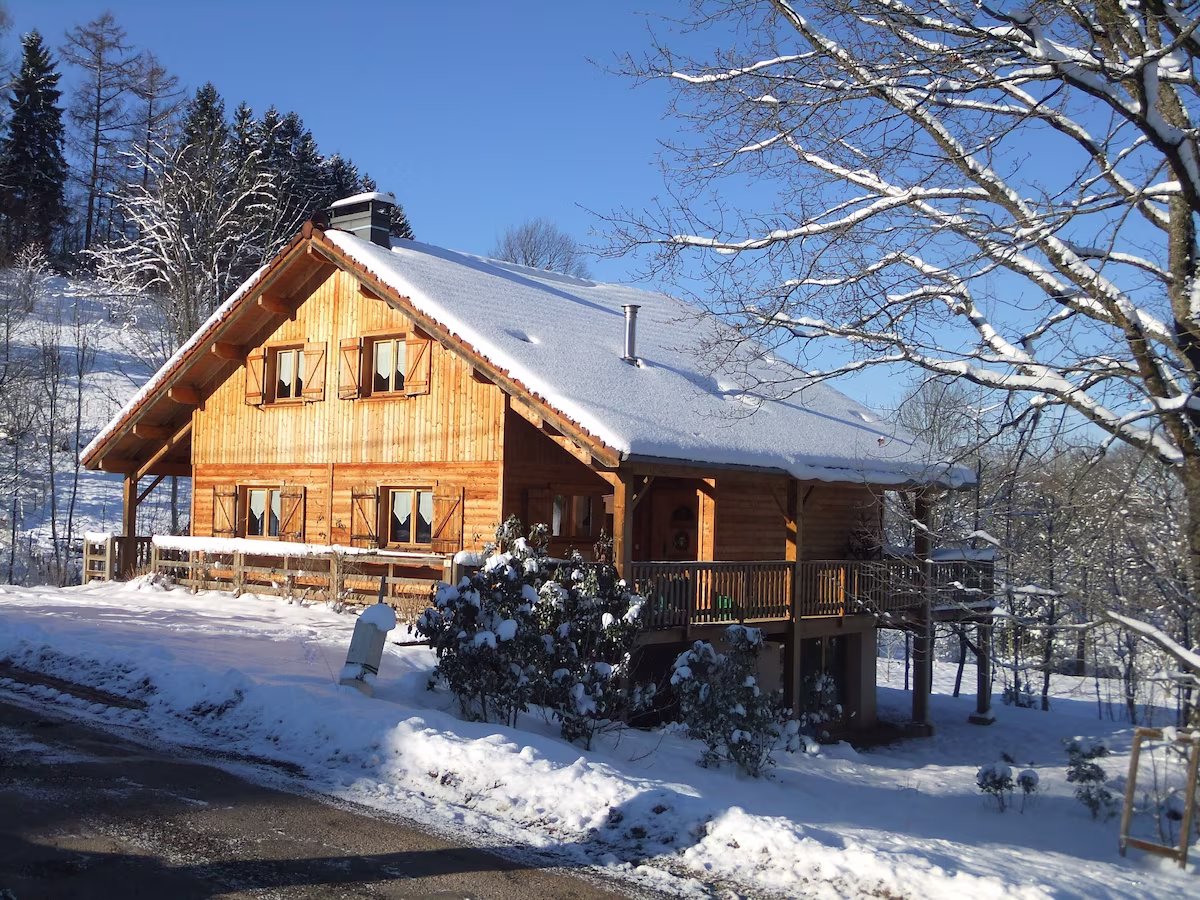 Wooden cabin with snow-covered roof in winter landscape.