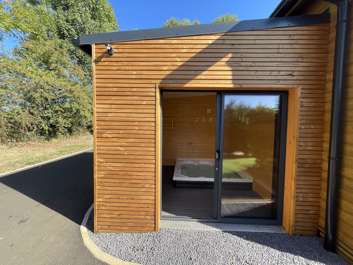 Eco Hot Tub Entrance Modern wooden building with glass door and patio.