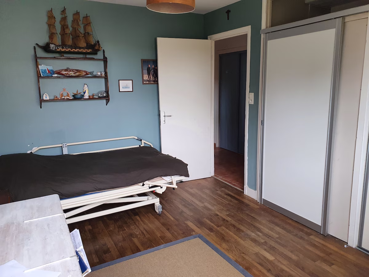 Room with bed, shelves, and wooden floor.