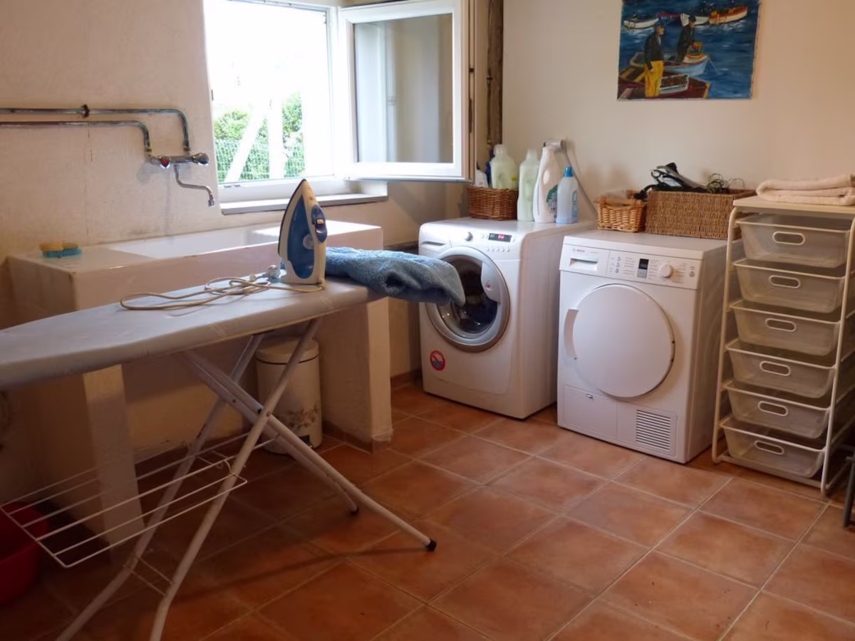 Laundry room with washing machine and ironing board.
