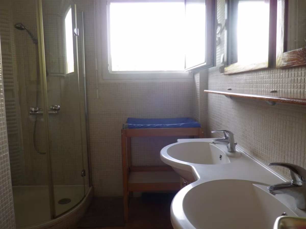 Modern bathroom with twin sinks and shower.