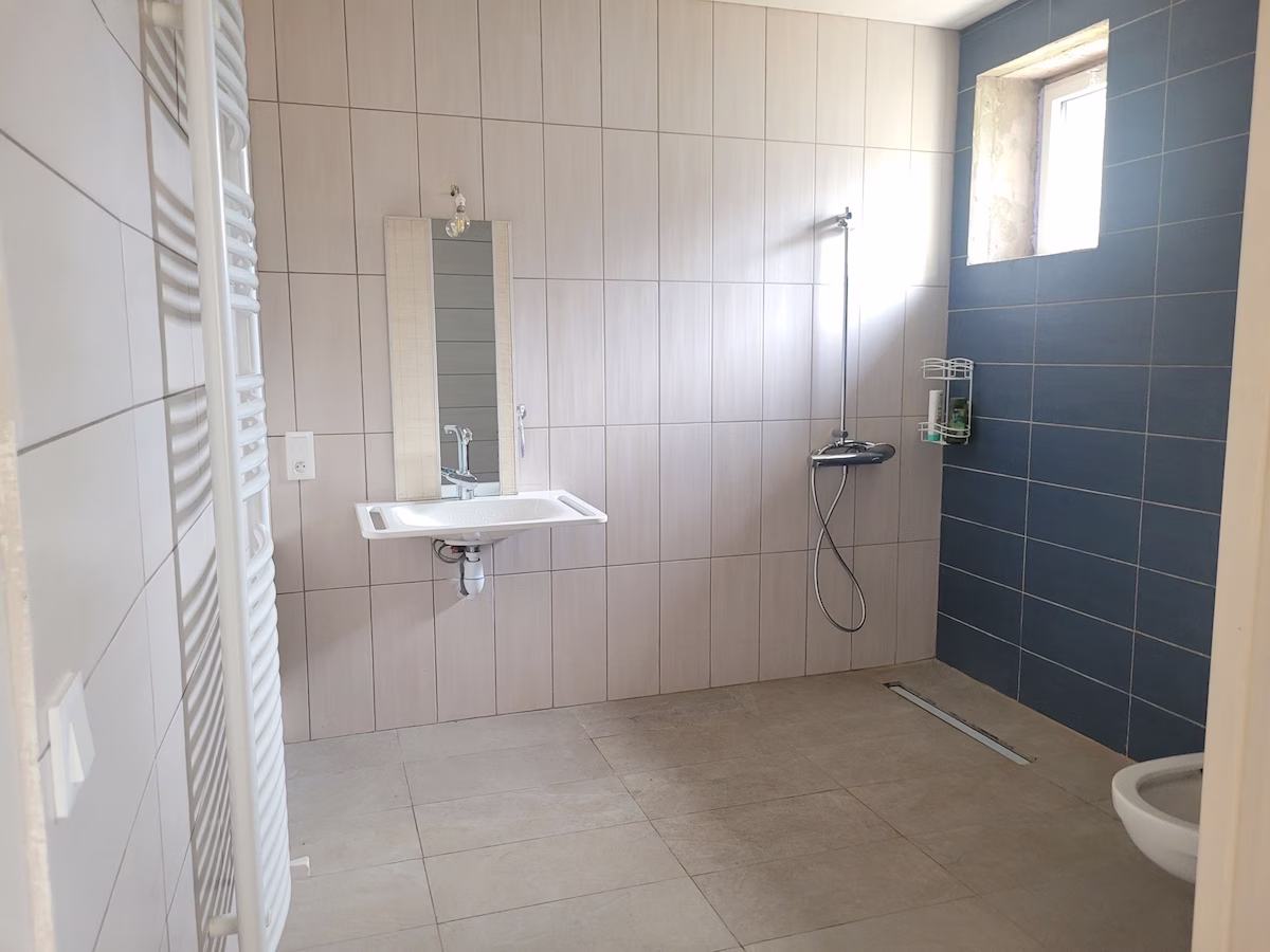 Spacious bathroom with sink, shower, and window