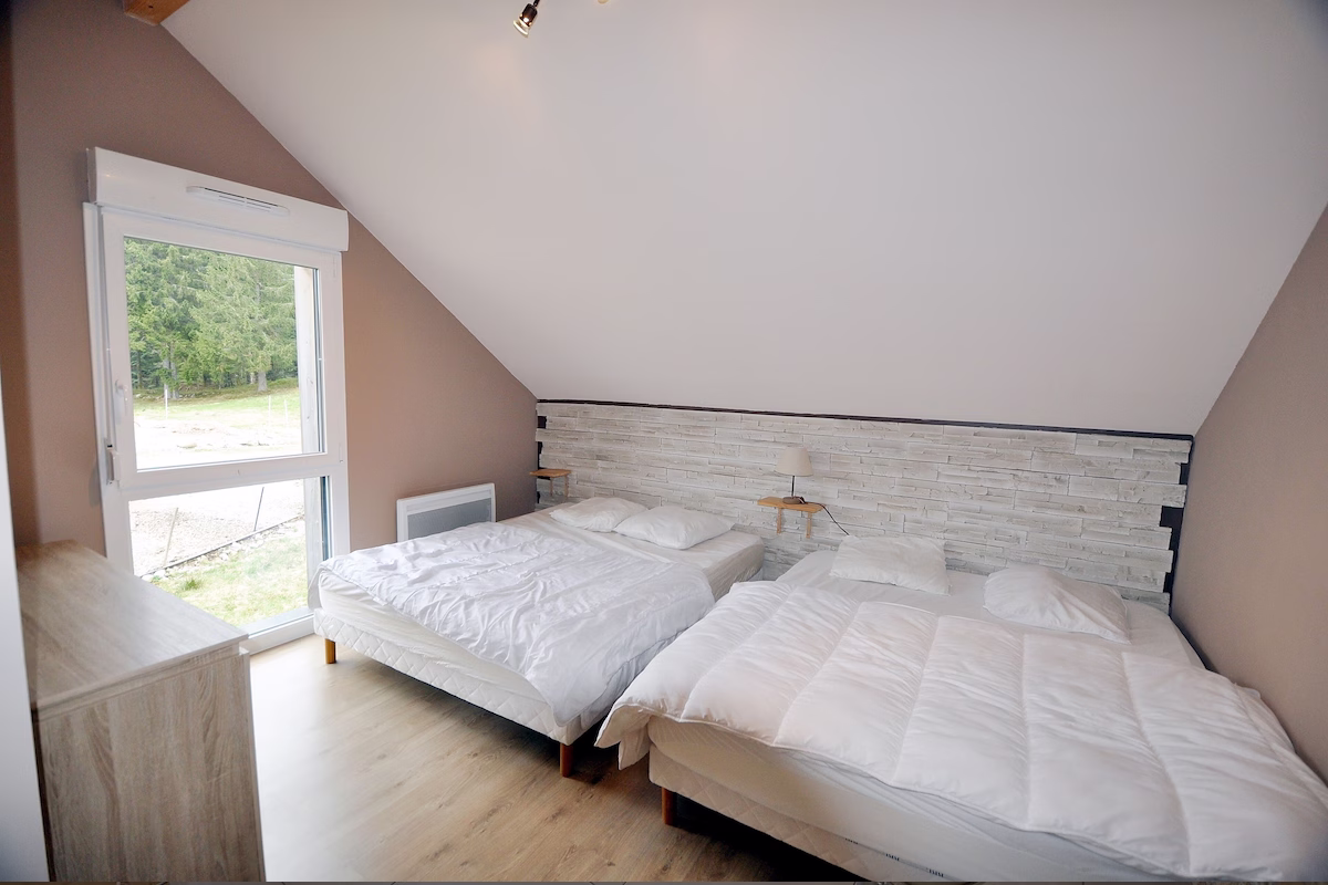 Cosy bedroom with two comfortable beds and window view.