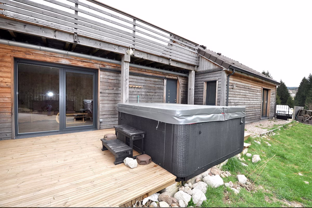 Wooden lodge with hot tub on deck.