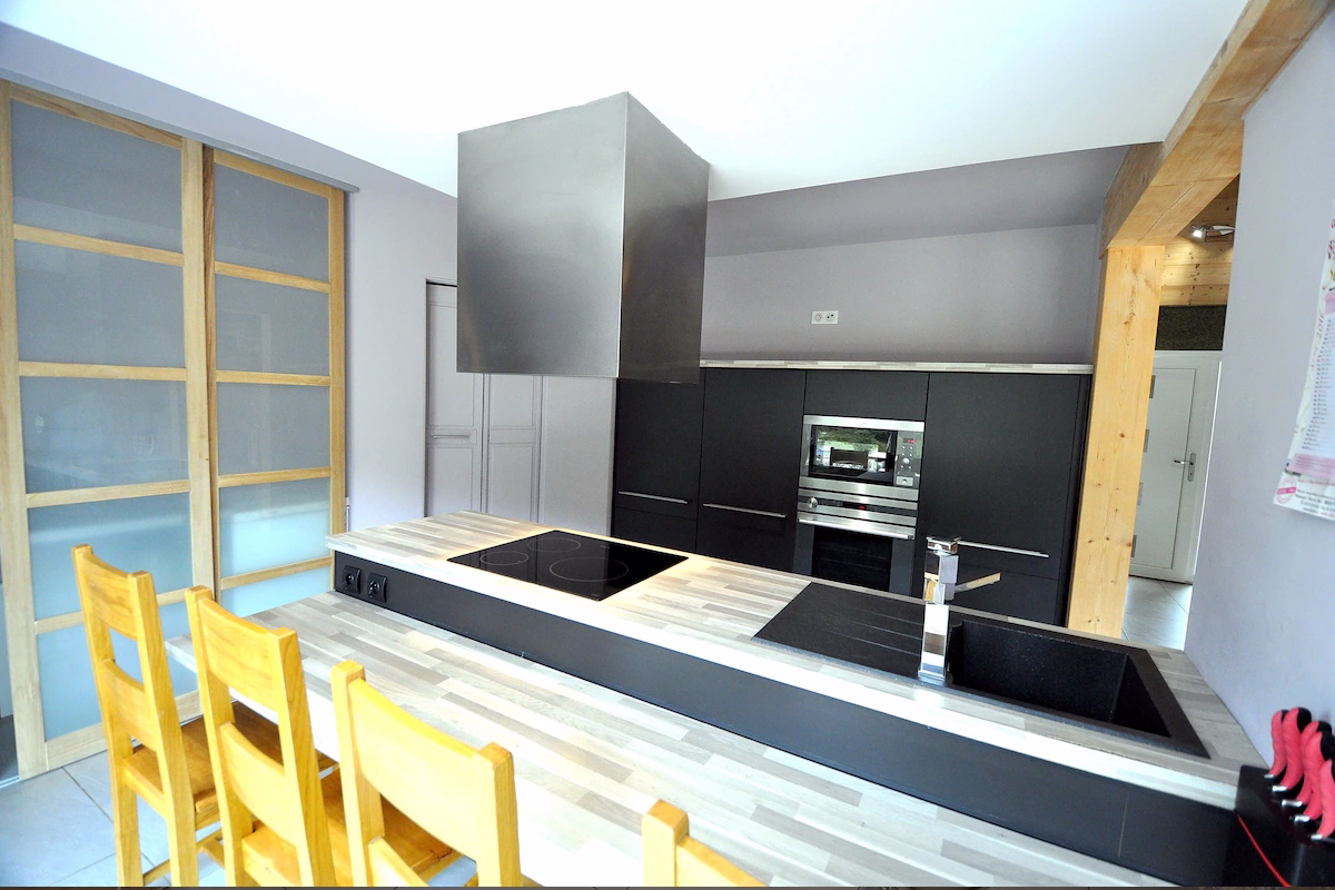 Modern kitchen with wooden bar stools and appliances.