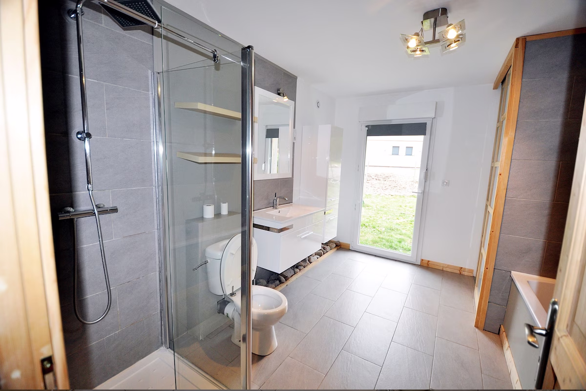 Modern bathroom with glass shower and natural light.