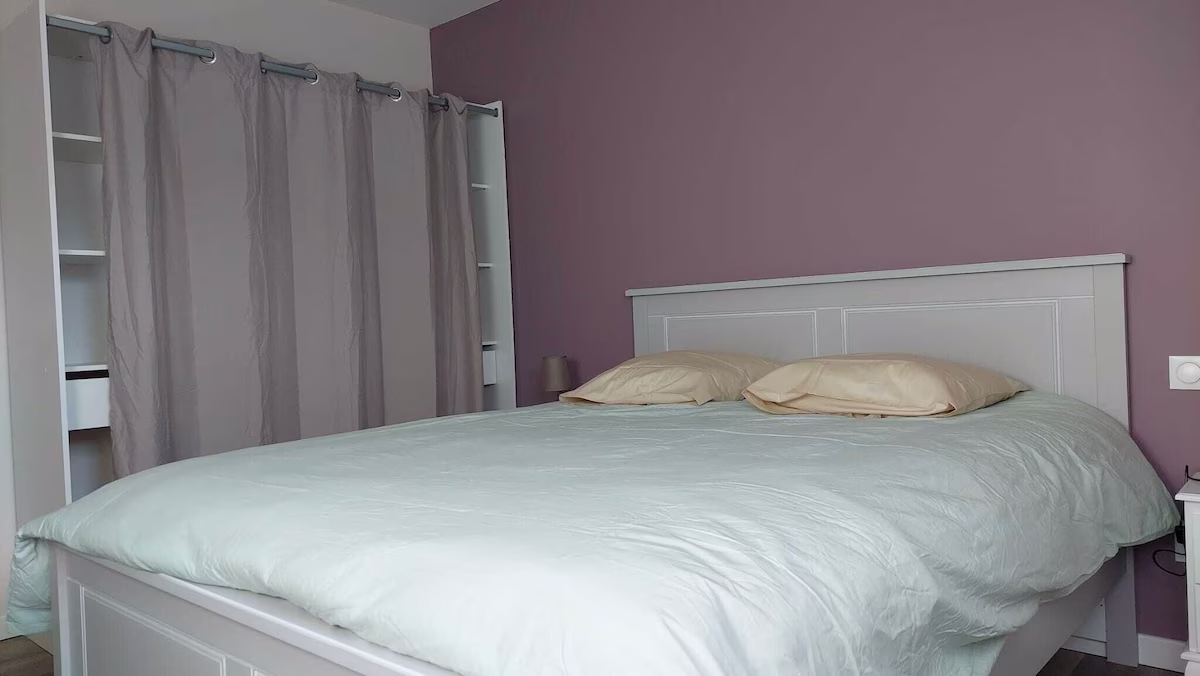 Modern bedroom with pastel colours and curtains.