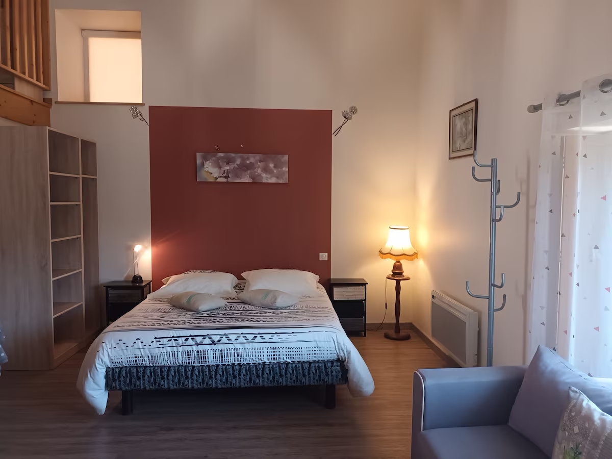 Spacious bedroom with double bed, sofa, and lamp.