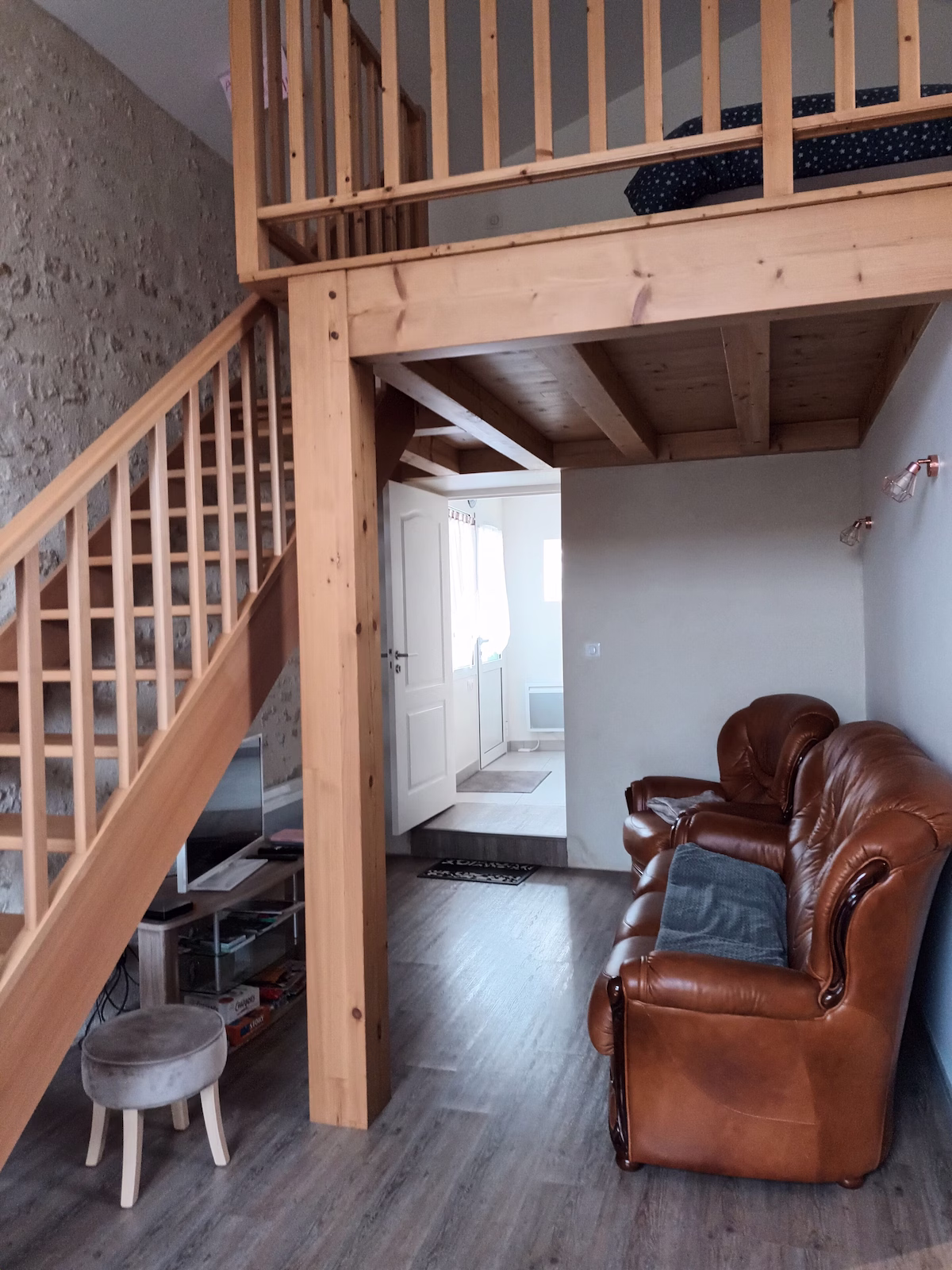 Cosy living room with wooden mezzanine and stairs.
