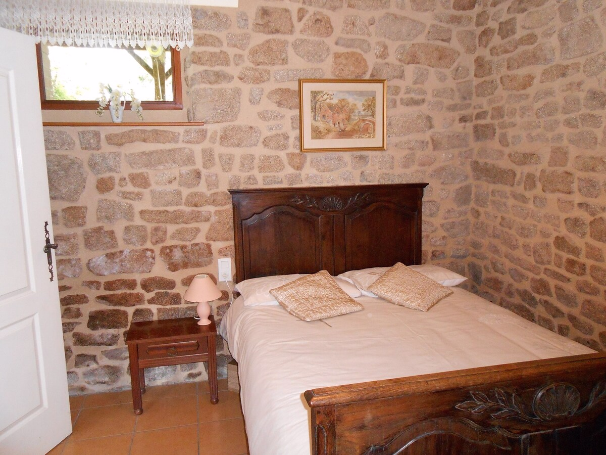 Cosy bedroom with stone walls and wooden furniture.