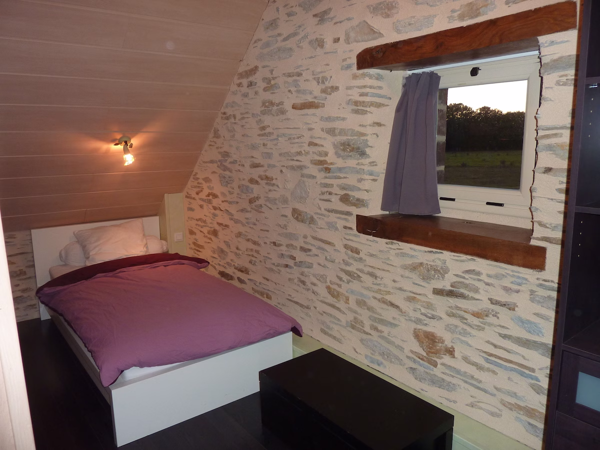 Cosy attic bedroom with stone walls and window.
