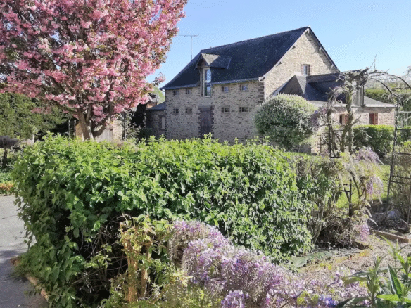 Stone cottage with garden and flowering trees.