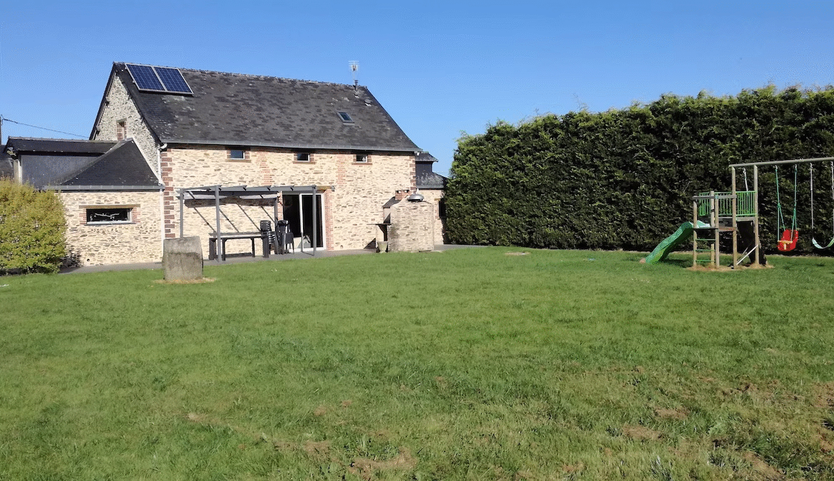 Stone house with solar panels and children's play area.